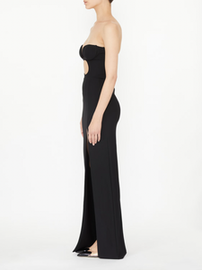 This black strapless evening dress by NENSI DOJAKA features a fitted silhouette that accentuates your figure with elegance. Crafted from high-quality Italian material, it showcases a distinctive keyhole neckline and a high slit, adding a refined and striking edge. The zip fastening at the back ensures a secure and tailored fit, making it an exceptional choice for sophisticated occasions.