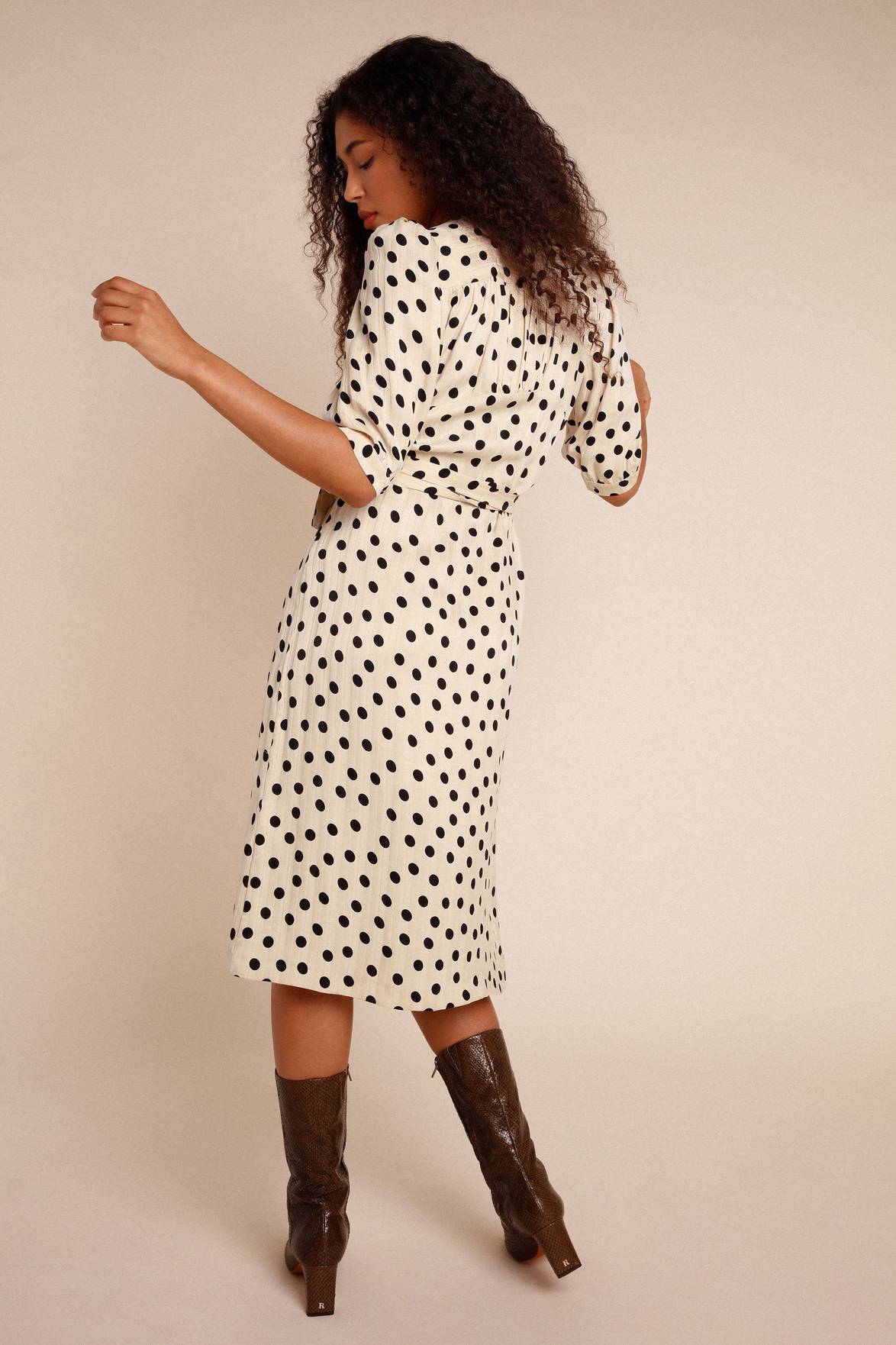 Introducing the Robe Caitlin - a stylish and versatile addition to your wardrobe. This knee-length jacquard dress features a wrap design, puffed sleeves, button accents, a waist-cinching belt, and back gathers for a flattering fit. Elevate any outfit with its playful polka dot pattern.