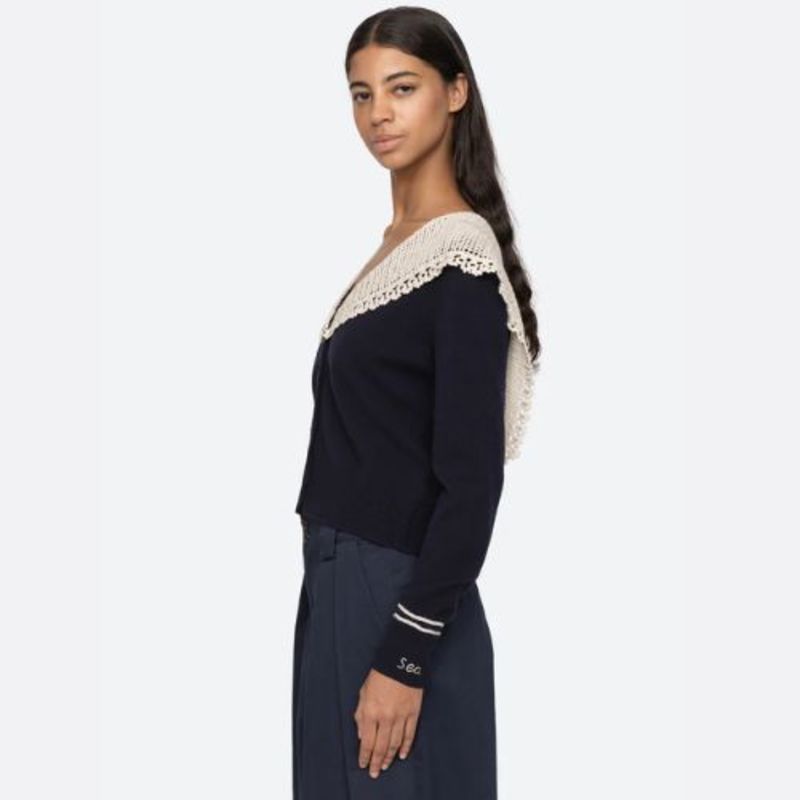 The Marie Cardigan by SEA combines effortless elegance with luxurious comfort. This sophisticated knit features a flattering v-neckline, intricate crochet capelet detail, and an embroidered 'Sea' logo on the cuff. Crafted from premium extra fine merino wool with cotton combo accents, it delivers a soft, breathable wear that moves with you. The relaxed button-front silhouette strikes the perfect balance between polished and comfortable, making it an essential layering piece for any wardrobe. 