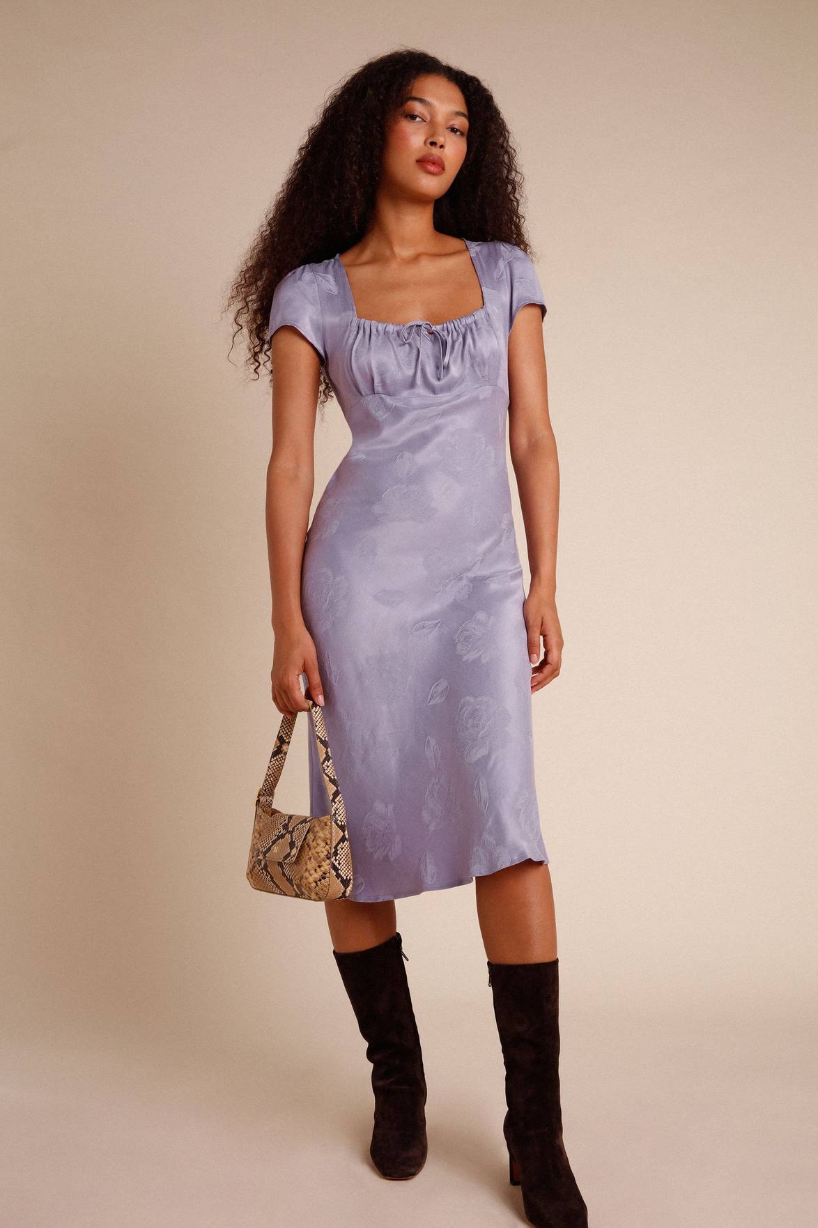 Introducing the versatile Robe Ines. This midi dress features a flattering gathered design on the chest with a unique knot detail. Its bias cut adds a touch of elegance, while the side zipper ensures a perfect fit. Available in lilac jacquard, this dress is the perfect addition to your wardrobe.