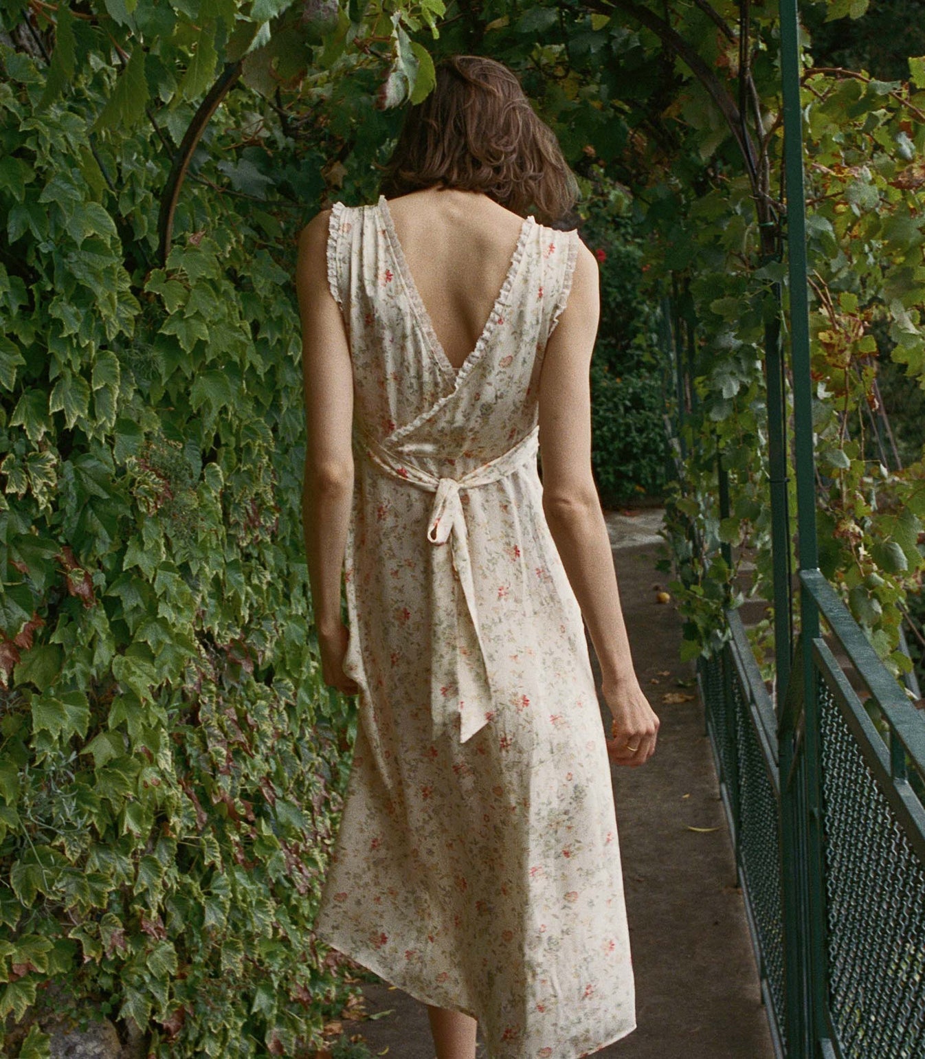 In a swingy silk-satin, the ‘30s-inspired Tahlia Dress—features a plunging V-neckline and surplice back trimmed with petite ruffles. A fitted bodice with an adjustable back waist tie gives way to an ankle-grazing bias-cut skirt, while a snap closure allows you to adjust the neckline.