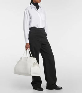 Introducing the Soft Margaux 17 Bag in White by The Row, now in luxurious grained leather. Handcrafted in Italy, this spacious tote is the perfect blend of style and comfort. Twin rolled handles, gusseted sides, and toggle closure make it both functional and fashionable. Upgrade your everyday with this must-have accessory.