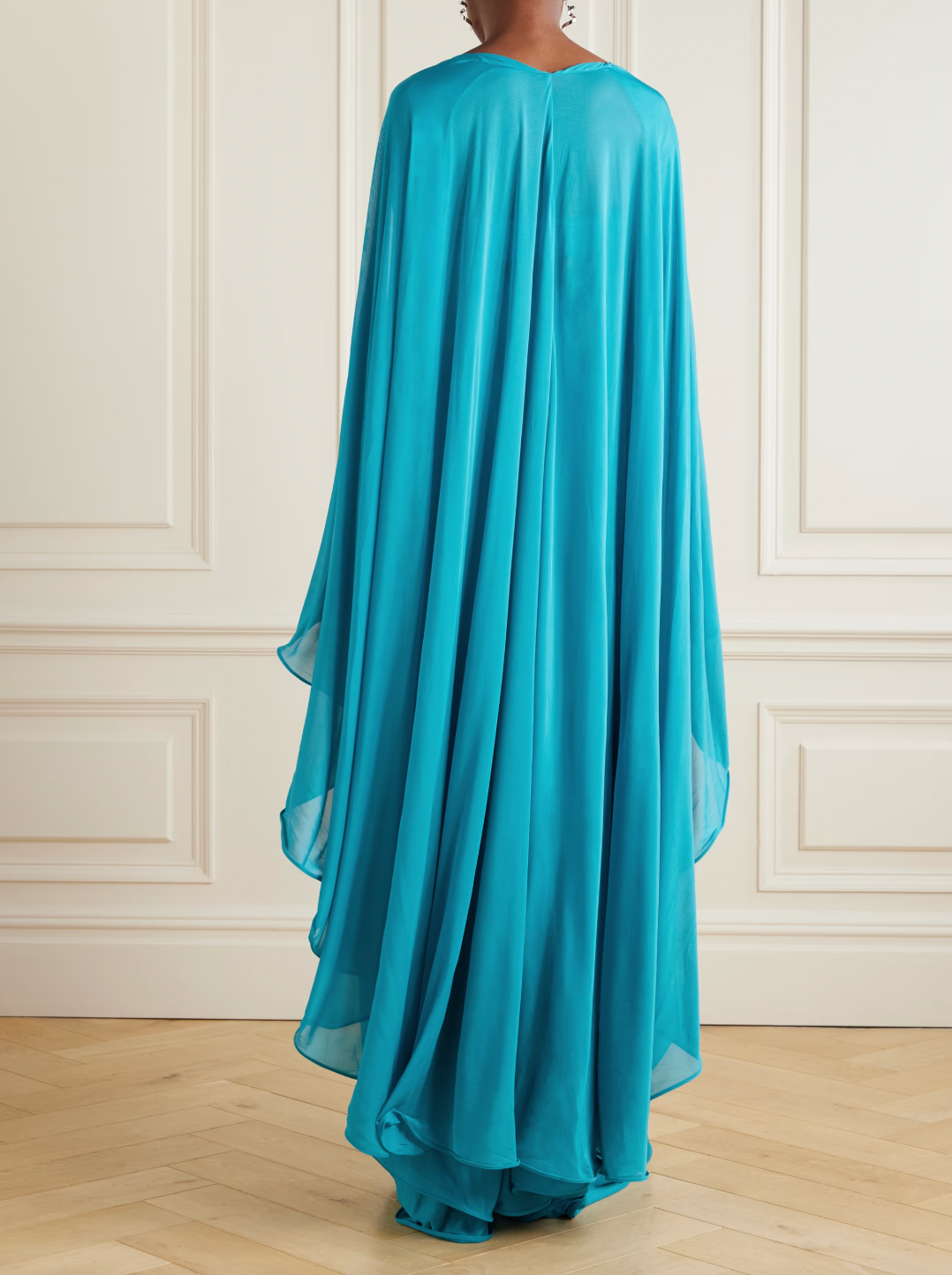 Experience the elegance of Christopher Esber’s Gyre dress, a stunning blend of volume and fluidity. Crafted from soft jersey, this maxi dress features a graceful cape-effect overlay and a bandeau bodice that cascades to a floor-length hem, creating effortless movement. Its vibrant turquoise hue draws attention, while the design’s delicate draping highlights your silhouette. Perfectly paired with silver jewelry, this statement piece embodies refined sophistication for any special occasion.