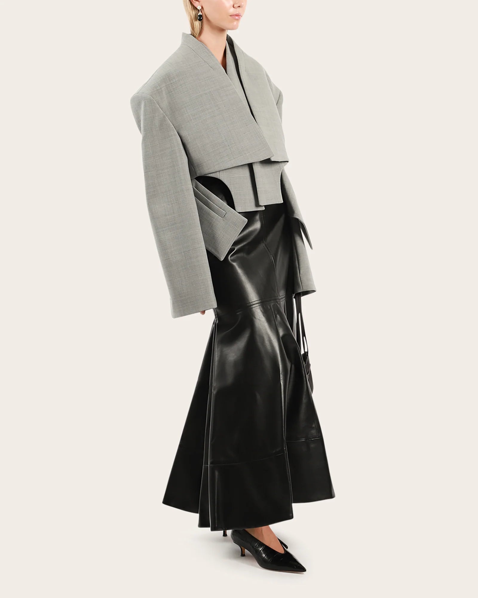 Elevate your wardrobe with this statement cropped jacket by Awake Mode that seamlessly blends bold design with everyday wearability. Featuring dramatic dropped shoulders, voluminous wide sleeves, and an attached insert vest, this piece commands attention while remaining surprisingly versatile. Strategic cutout details at the front create an asymmetrical silhouette that flatters and intrigues, while practical side pockets keep you functional. 