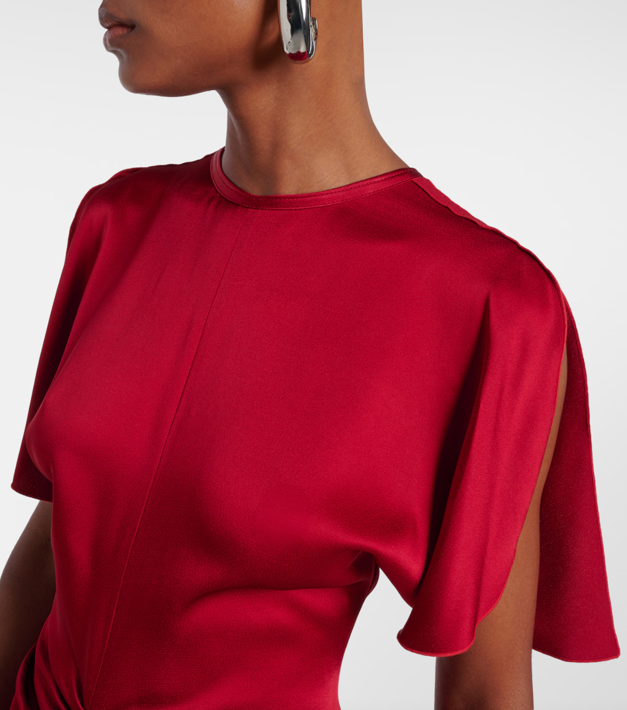 Stunning in vibrant red crêpe satin, this Victoria Beckham gown masterfully balances elegance with edge. Dramatic cape shoulders provide modest coverage while the daring open back commands attention—a sophisticated contrast that turns heads. Expertly gathered detailing sculpts a flattering hourglass silhouette, making this the perfect statement piece for unforgettable evenings. Timeless design meets modern allure.