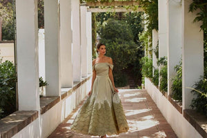 Indulge in luxury with the Aurora Gown, a soft pistachio dress made of satin fabric that exudes elegance and femininity. The open shoulders and sophisticated sleeves highlight your features while the crystal decorated hem adds a touch of brilliance. Hand-cut rose petals create a voluminous and unique look, perfect for any special occasion.