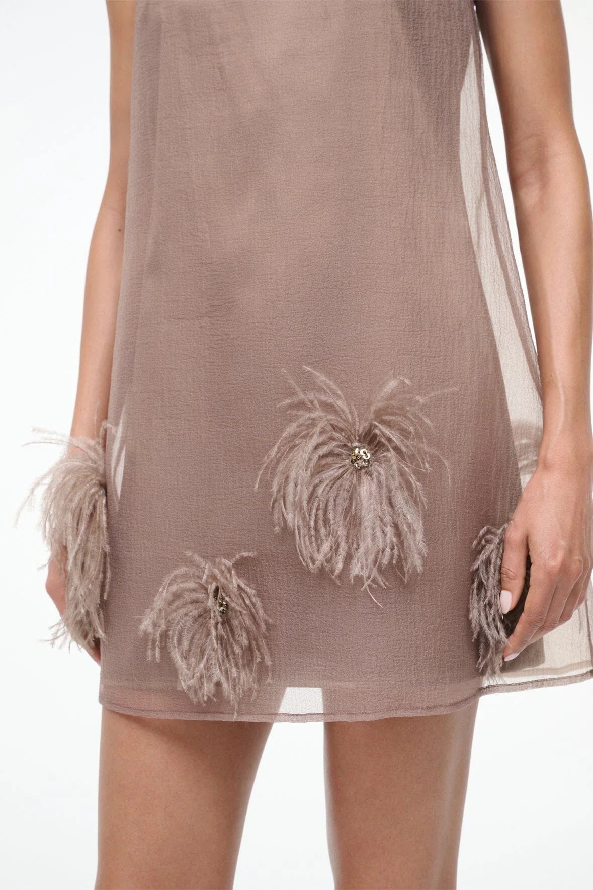 The STAUD Albee Mini Dress in Truffle is an effortlessly elegant piece that combines sophistication with modern style. This sleeveless organza dress features a refined high neckline and a functional tie closure at the back, creating a flattering silhouette with subtle movement. The sheer fabric is beautifully balanced by an interior slip, offering both transparency and coverage for versatile styling. Perfect for elevated occasions or layered looks, this mini dress brings understated luxury to your wardrobe.