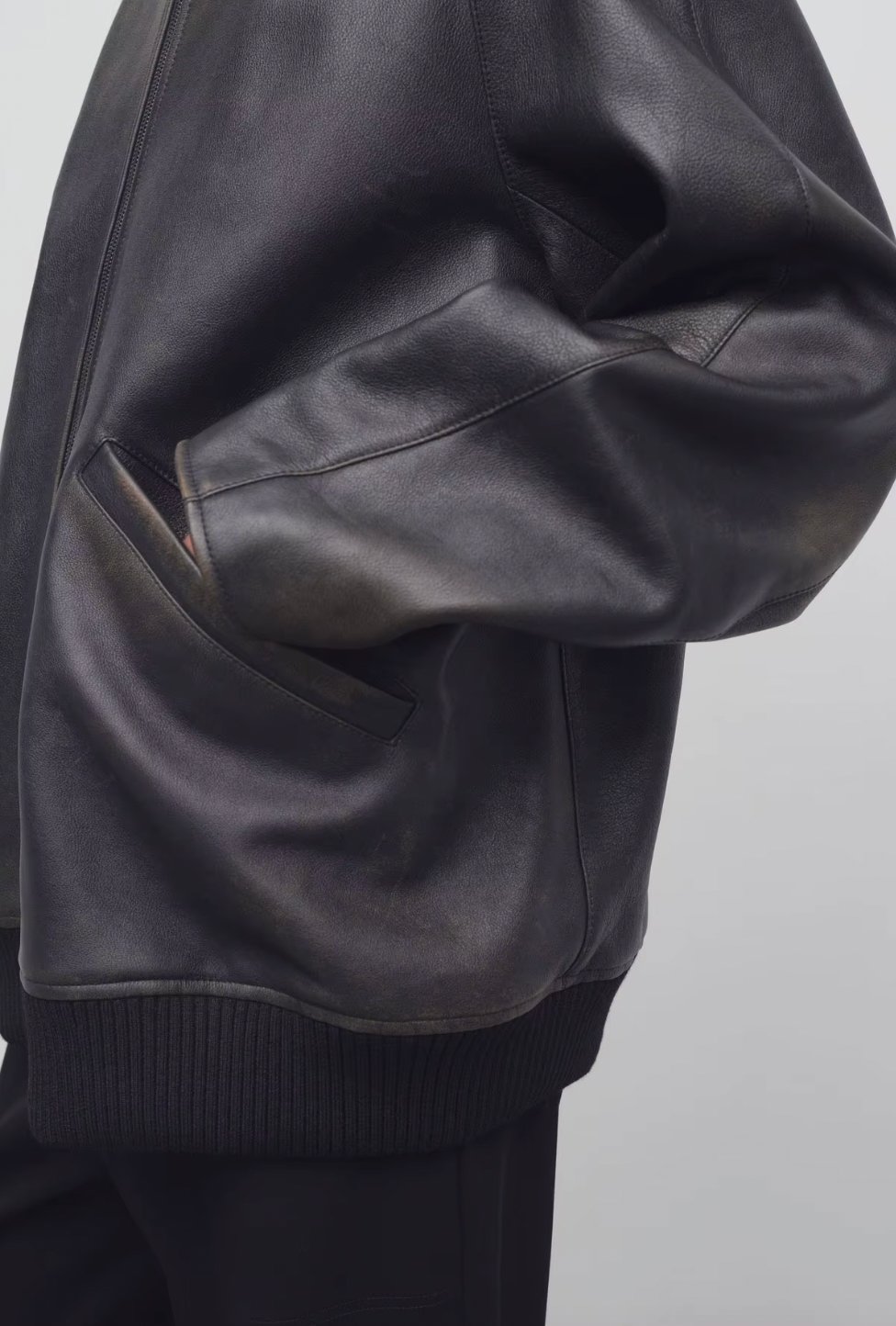 The Row brown oversized motorcycle jacket in distressed calfskin leather with stand collar, raglan sleeves, side welt pockets, and ribbed hem. Finished with silver-toned front and interior cuff zippers. This jacket comes fully lined in silk Habotai.