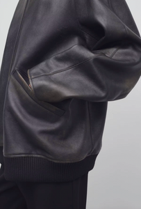 The Row brown oversized motorcycle jacket in distressed calfskin leather with stand collar, raglan sleeves, side welt pockets, and ribbed hem. Finished with silver-toned front and interior cuff zippers. This jacket comes fully lined in silk Habotai.