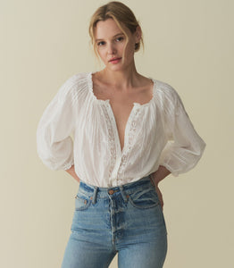 Crafted from a 100% organic cotton voile, the Abigail Top features a breezy silhouette, a round neckline, and buttons running down the center front. Billowy sleeves trimmed with scalloped lace hit just above the wrist, while alternating pintuck clusters, lace, and delicate floral embroidery decorate the front. Leave it loose, or tuck it into your favorite pair of high-waisted jeans.