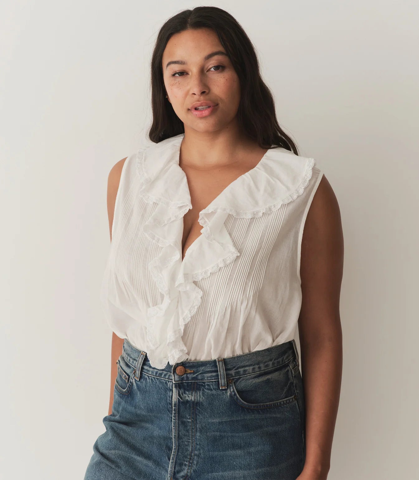 Indulge in the elegance of DOEN's Hilda Top. Made from organic cotton, this white voile top features a concealed front button fastening and delicate lace trim. Plisse details and a ruffle collar add a touch of sophistication. Perfect for a luxurious and stylish look