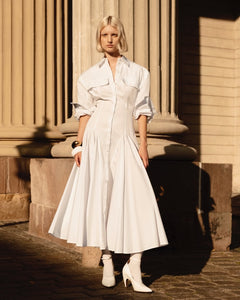 Elevate your style with the luxurious Godet Shirt Dress by Helsa. Made from premium poplin, this partially lined dress boasts a flattering fit and flare silhouette. With buttoned cuffs, front button closure, and flap pockets, it's a sophisticated and elegant must-have for your wardrobe.