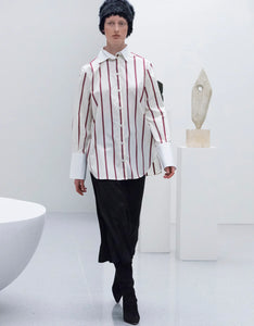 Unleash your business savvy with the 'Sassa' stripe shirt from Toteme. This stylish piece features bold burgundy stripes on a crisp white base, with a classic button-through design and oversized fit. Complete with a subtle monogram on the collar and a curved split hem, this shirt is the perfect balance of sophistication and playfulness. Get ready to make a statement in this must-have piece!