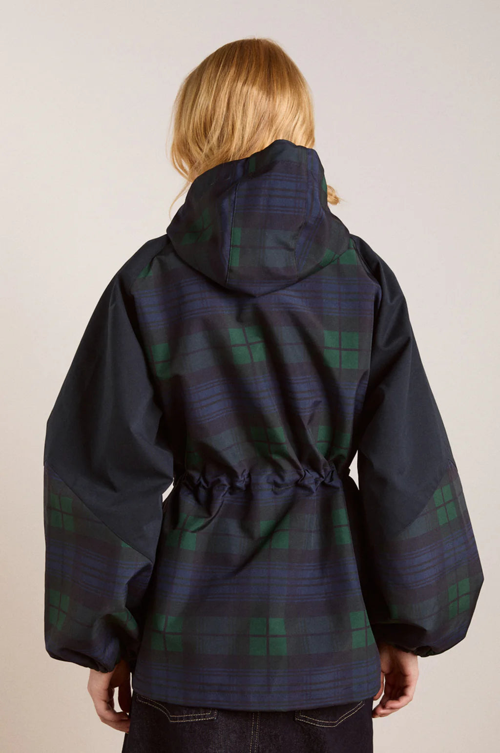 Embrace rainy days with the Liu Coat from Damson Madder, featuring a classic Black Watch tartan design crafted from shower-resistant fabric. Its balloon-style cuffs, adjustable hood, and cinchable waist offer both comfort and a flattering silhouette, while signature 'DM' embroidery adds a touch of distinction. Equipped with practical pockets and thoughtful details, this coat effortlessly combines style and functionality, making it the perfect shield against wet weather.