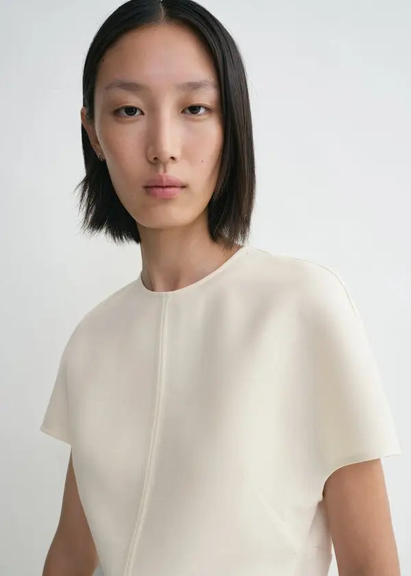 Elevate your wardrobe with this sophisticated TOTEME cap-sleeve top, designed for the modern woman who values refined elegance. The longline silhouette flatters your frame while the distinctive twisted seams add architectural interest to every wear. Crafted from luxurious double-faced cady blended with wool and silk, this piece offers both comfort and durability. The concealed back zipper ensures a seamless, polished look. 