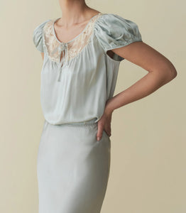 The luxurious Camri Top exudes an effortless style and understated elegance. Crafted from buttery silk satin, it features short puffed sleeves and delicate lace detailing at the yoke. Inspired by the glamour of the 1930s, it is completed with a delicate silk satin tie at the center front. Elevate your wardrobe with this timeless piece.