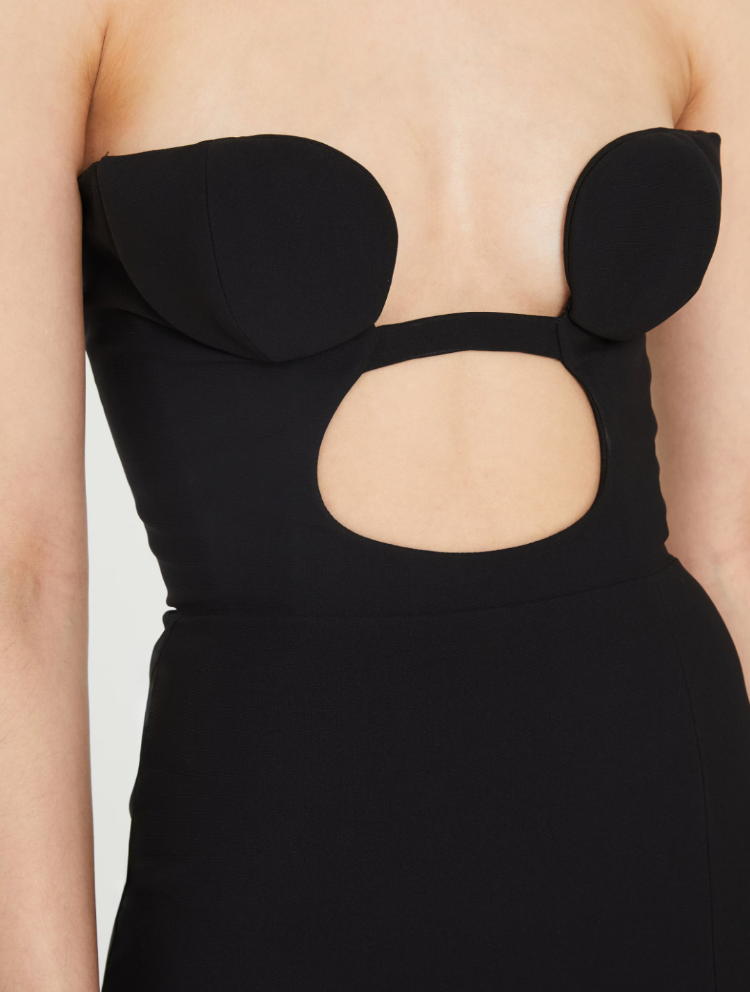 This black strapless evening dress by NENSI DOJAKA features a fitted silhouette that accentuates your figure with elegance. Crafted from high-quality Italian material, it showcases a distinctive keyhole neckline and a high slit, adding a refined and striking edge. The zip fastening at the back ensures a secure and tailored fit, making it an exceptional choice for sophisticated occasions.
