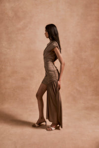 The Ravenna Mini Dress in Taupe offers a graceful silhouette with its asymmetrical high-low hemline and ruched detailing. Designed to fit true to size, this sleeveless, form-fitting dress effortlessly enhances your natural shape, making it ideal for special events. Its elegant taupe color pairs beautifully with gold or silver jewelry and classic pumps, ensuring a polished and confident look every time.