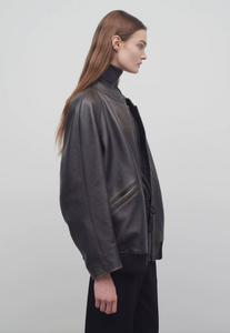 The Row brown oversized motorcycle jacket in distressed calfskin leather with stand collar, raglan sleeves, side welt pockets, and ribbed hem. Finished with silver-toned front and interior cuff zippers. This jacket comes fully lined in silk Habotai.