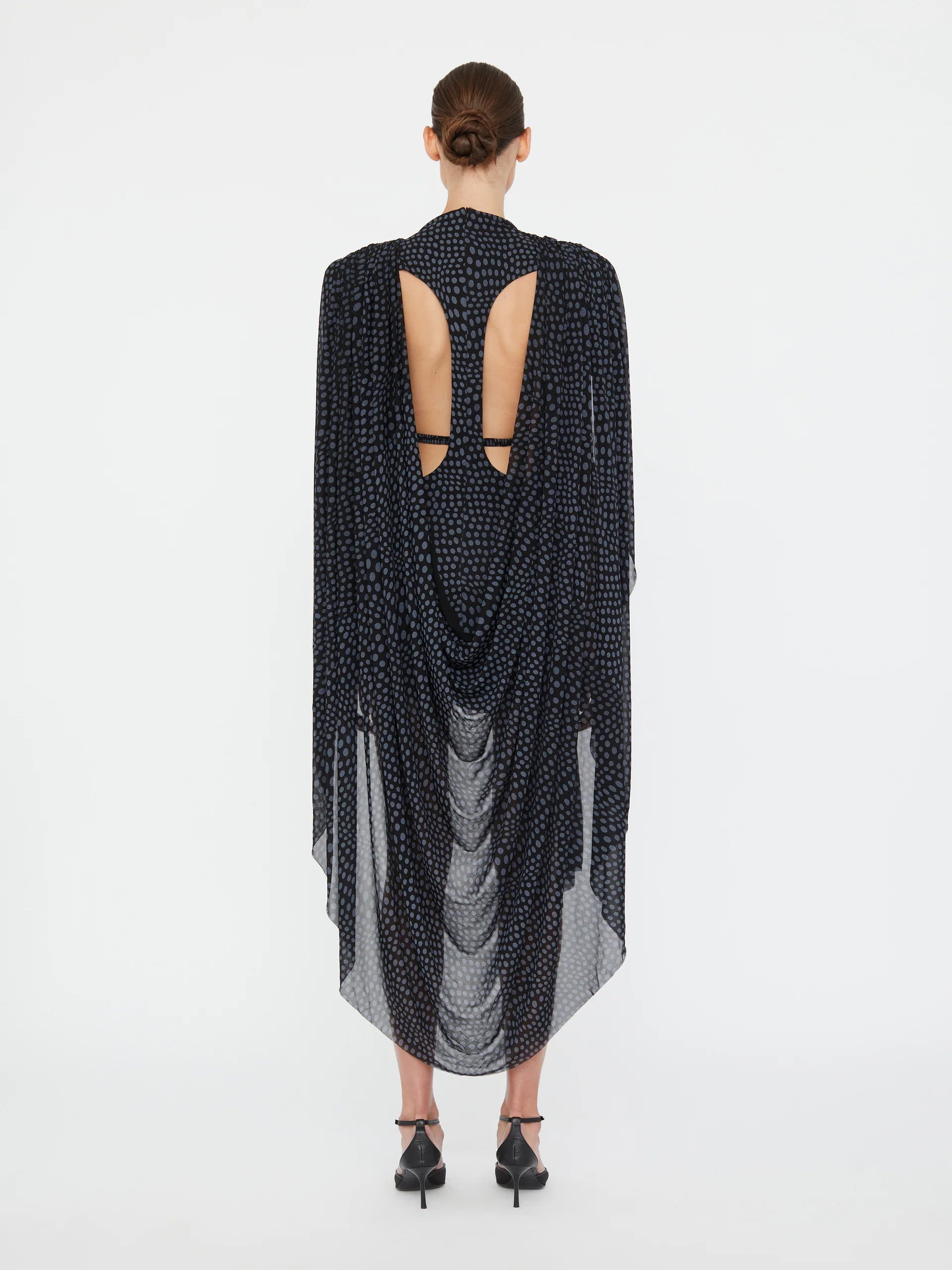 Embrace a nostalgic 90s vibe with the Torrent Draped Mini Dress by Christopher Esber, featuring a striking blue on black warped polka dot pattern inspired by a summer rain shower. The mini silhouette, enriched with gathered and cinched drapes, creates dynamic movement and captivating dimension. Its asymmetric draped skirt and fully lined construction offer effortless style and comfort, making it the perfect choice for standing out with subtle, artistic flair. 