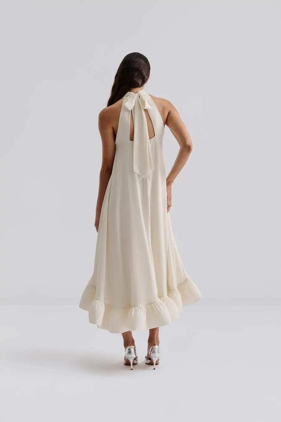 Das Sabrina Halterneck Brautkleid kombiniert zeitlose Eleganz mit romantischem Charme. Das leichte Neckholder-Maxikleid mit offenem Rücken und fließendem, sanft gerüschtem Rock sorgt für eine feminine Silhouette und einen unvergesslichen Auftritt. Der Schleifenverschluss am Nacken setzt Ihre Schultern gekonnt in Szene und macht es zur perfekten Wahl für standesamtliche Trauungen, Sommerhochzeiten oder festliche Anlässe. Fühlen Sie sich mühelos schön und strahlen Sie an Ihrem besonderen Tag.