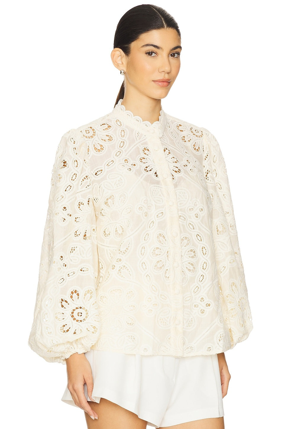 Elevate your everyday style with the Rhiannon Embroidered Blouse by Zimmermann, a charming piece that combines timeless elegance with modern flair. Featuring delicate floral embroidery that adorns the entire design, this blouse makes a sophisticated statement. The romantic puff sleeves with elastic cuffs create a flattering silhouette while maintaining comfort throughout the day. A convenient front button closure allows for effortless dressing and styling versatility. 
