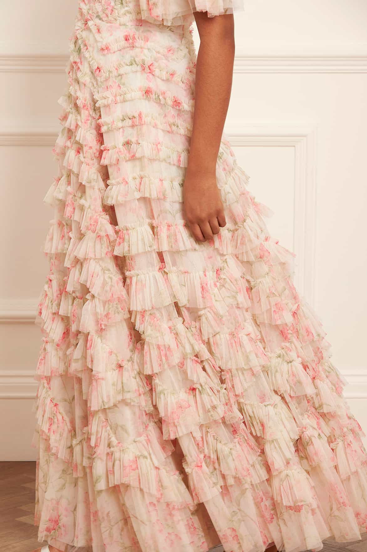 Indulge in the whimsical beauty of the Lana Off-Shoulder Gown. A hand-painted print of sunset and pink peonies adorns this signature Needle &amp; Thread style, while gathered frills add a romantic touch. The off-shoulder design with elasticated panels and layers of soft tulle creates a statement look. Plus, an internal corset with stretch power mesh ensures comfort and perfect fit.