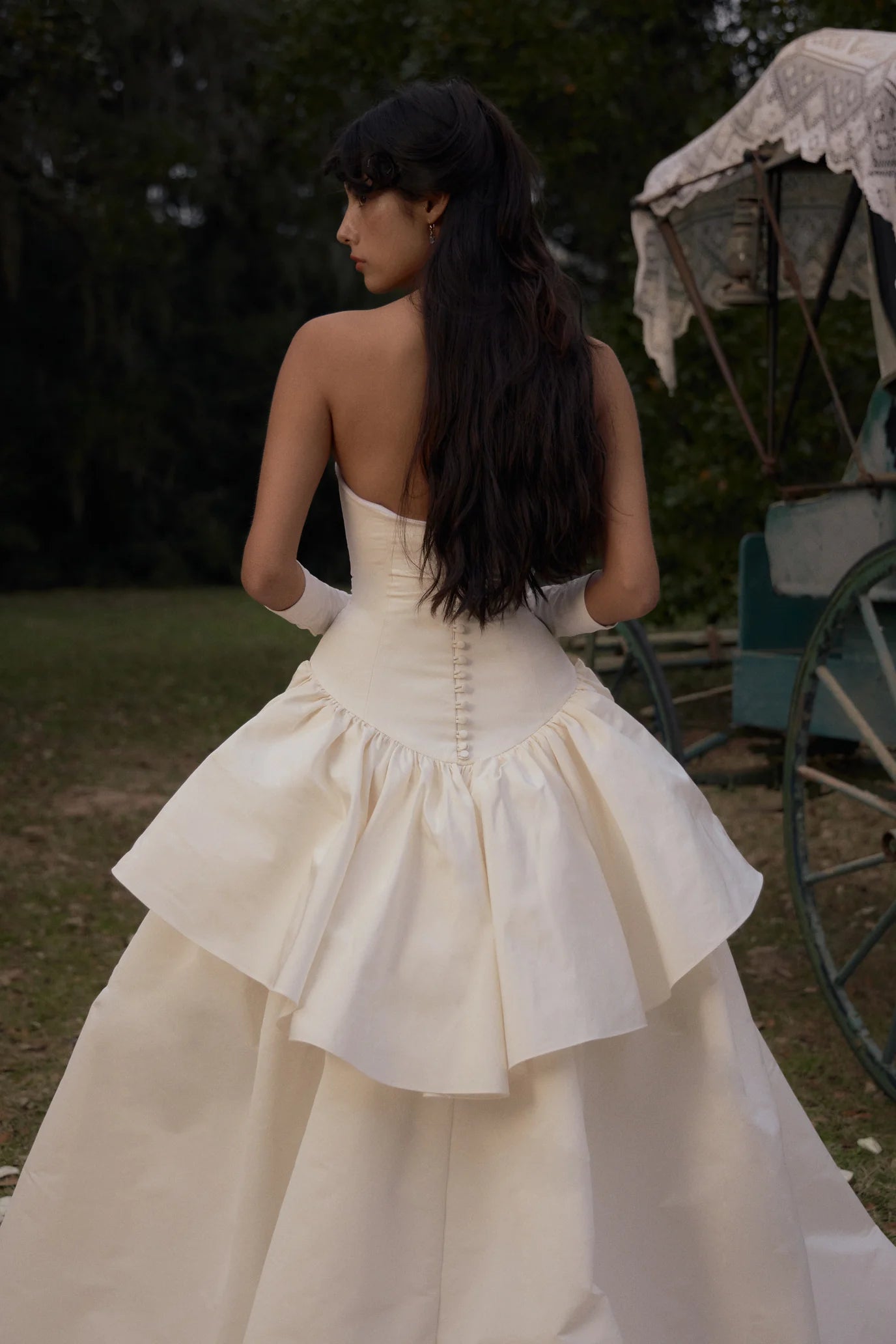 Elevate your style with our Funny Face Gown in Ivory. This strapless column gown features side bustles and a back peplum, enhanced by a built-in corset and hip padding. The fully functional buttons and invisible zipper add effortless elegance. Stand out in this unique and flattering design!