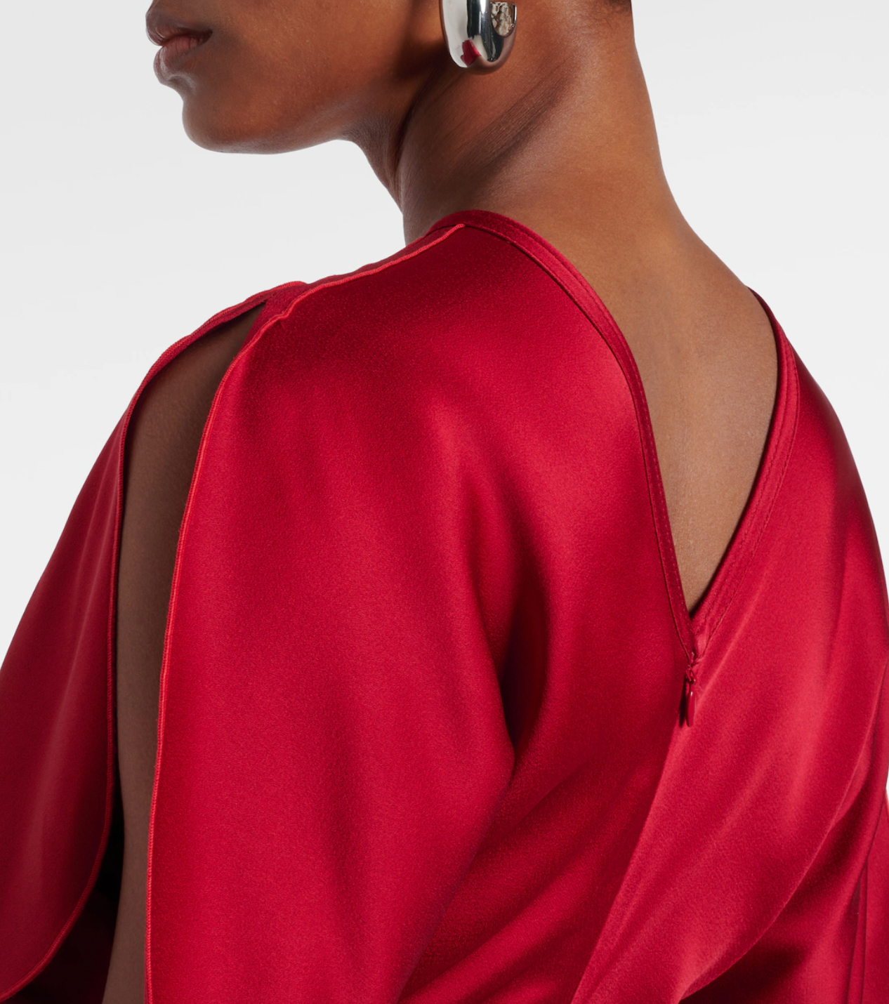 Stunning in vibrant red crêpe satin, this Victoria Beckham gown masterfully balances elegance with edge. Dramatic cape shoulders provide modest coverage while the daring open back commands attention—a sophisticated contrast that turns heads. Expertly gathered detailing sculpts a flattering hourglass silhouette, making this the perfect statement piece for unforgettable evenings. Timeless design meets modern allure.