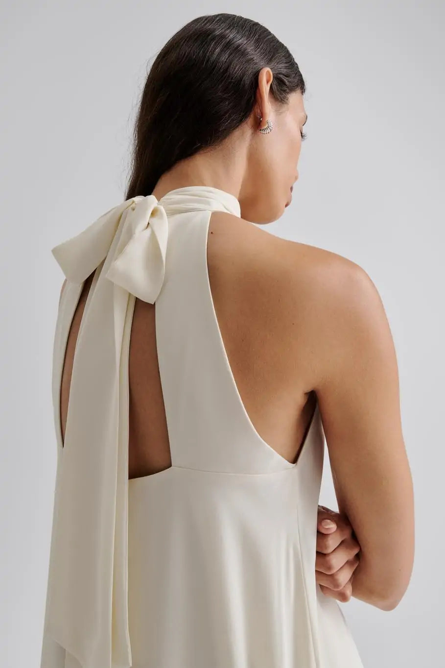 Das Sabrina Halterneck Brautkleid kombiniert zeitlose Eleganz mit romantischem Charme. Das leichte Neckholder-Maxikleid mit offenem Rücken und fließendem, sanft gerüschtem Rock sorgt für eine feminine Silhouette und einen unvergesslichen Auftritt. Der Schleifenverschluss am Nacken setzt Ihre Schultern gekonnt in Szene und macht es zur perfekten Wahl für standesamtliche Trauungen, Sommerhochzeiten oder festliche Anlässe. Fühlen Sie sich mühelos schön und strahlen Sie an Ihrem besonderen Tag.