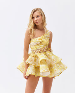 The Iris Mini Dress by YVON combines premium linen silk fabric with a delicate yellow floral print inspired by fairy forest blossoms. Its handcrafted asymmetrical bodice enhances feminine contours with refined subtlety, while the adjustable waist lacing ensures a perfectly sculpted silhouette. This dress expertly merges romantic elements with sophisticated craftsmanship, making it an exceptional choice for those seeking elegance with distinctive style.