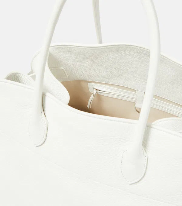 Introducing the Soft Margaux 17 Bag in White by The Row, now in luxurious grained leather. Handcrafted in Italy, this spacious tote is the perfect blend of style and comfort. Twin rolled handles, gusseted sides, and toggle closure make it both functional and fashionable. Upgrade your everyday with this must-have accessory.