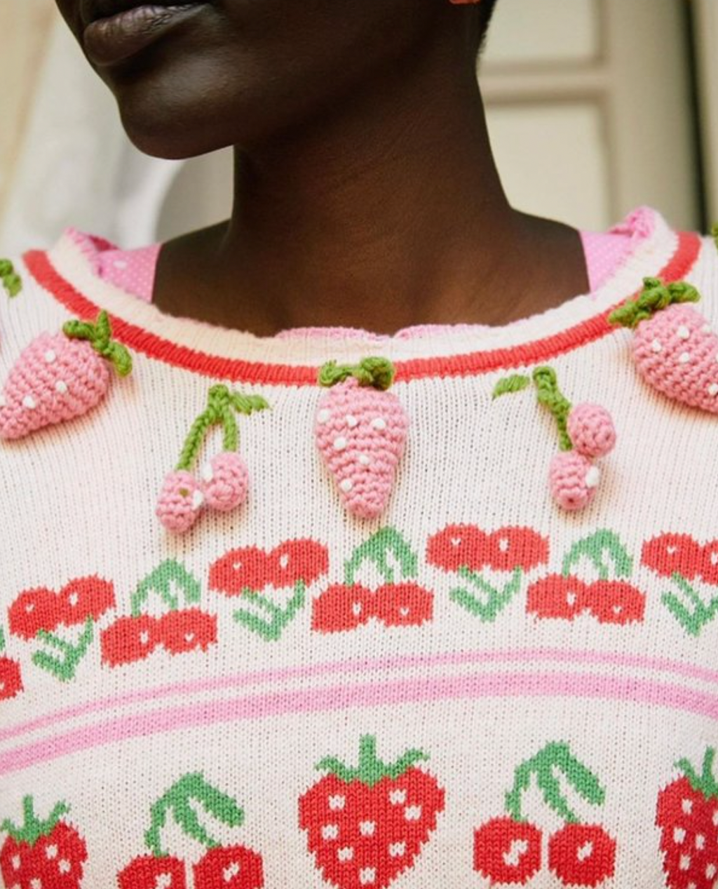 The Renton Pullover is a charming blend of cotton and wool, adorned with a delightful strawberry and cherry motif. Hand-crocheted strawberries add a touch of whimsy. With a shrunken fit and ribbed neckline, cuffs, and border, this sweater is both cozy and stylish. Adorned with strawberry buttons down the back, it's the perfect addition to any wardrobe.