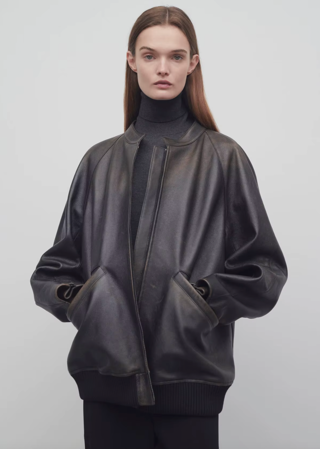 The Row brown oversized motorcycle jacket in distressed calfskin leather with stand collar, raglan sleeves, side welt pockets, and ribbed hem. Finished with silver-toned front and interior cuff zippers. This jacket comes fully lined in silk Habotai.
