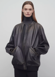 The Row brown oversized motorcycle jacket in distressed calfskin leather with stand collar, raglan sleeves, side welt pockets, and ribbed hem. Finished with silver-toned front and interior cuff zippers. This jacket comes fully lined in silk Habotai.