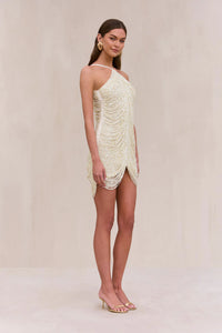 Indulge in the luxurious and exclusive Domina Dress by Cult Gaia. This exquisite halter dress boasts a layered and draped faux pearl fringe that gracefully moves with you. The plunging open back and flattering v-cut silhouette make this mini dress a must-have for any elegant occasion. Elevate your style with this captivating piece.