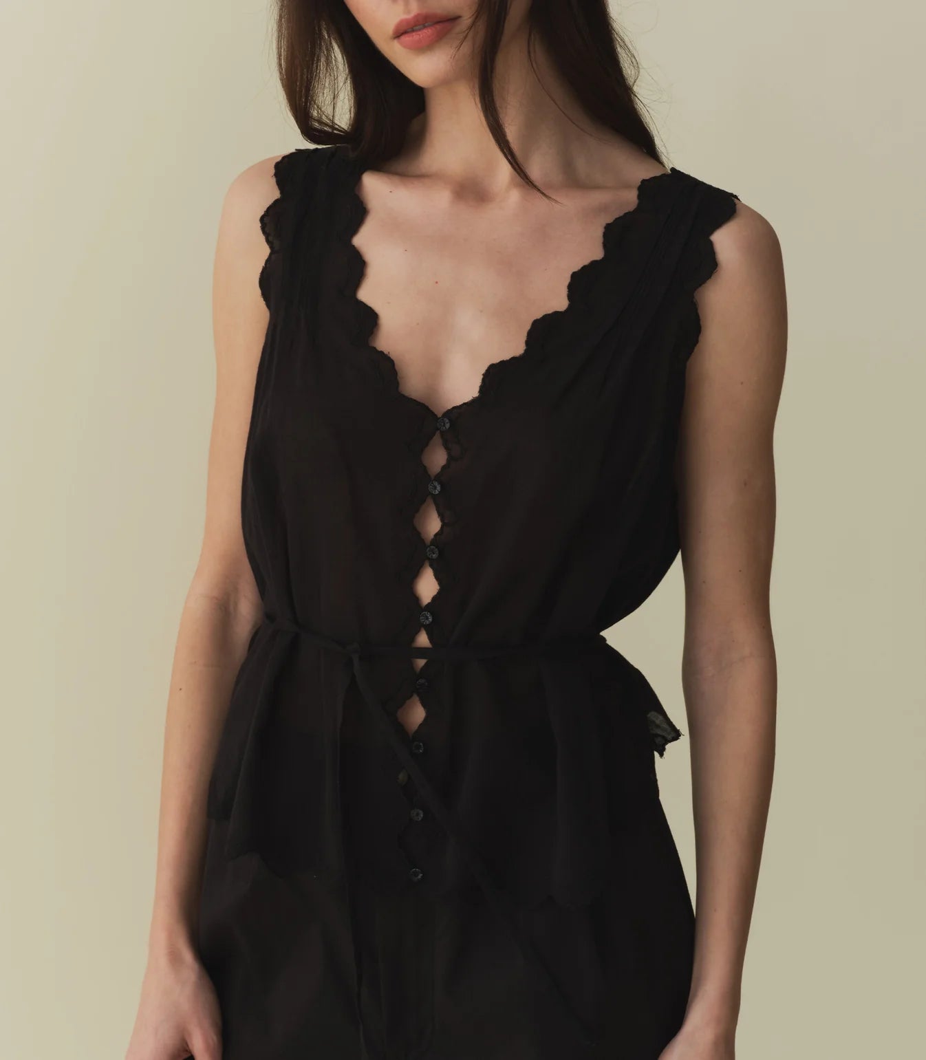 Crafted from the softest organic cotton voile, the Aldora Top is a sleeveless style with a plunging V-neckline, a slightly cropped hem, and scallop embroidery trim. A line of flower-shaped mother-of-pearl buttons extend down the front, while playful cut-outs allow for a glimpse of skin. Clustered pintucks lend texture to the shoulders and back, while a back waist tie allows you to adjust the fit.