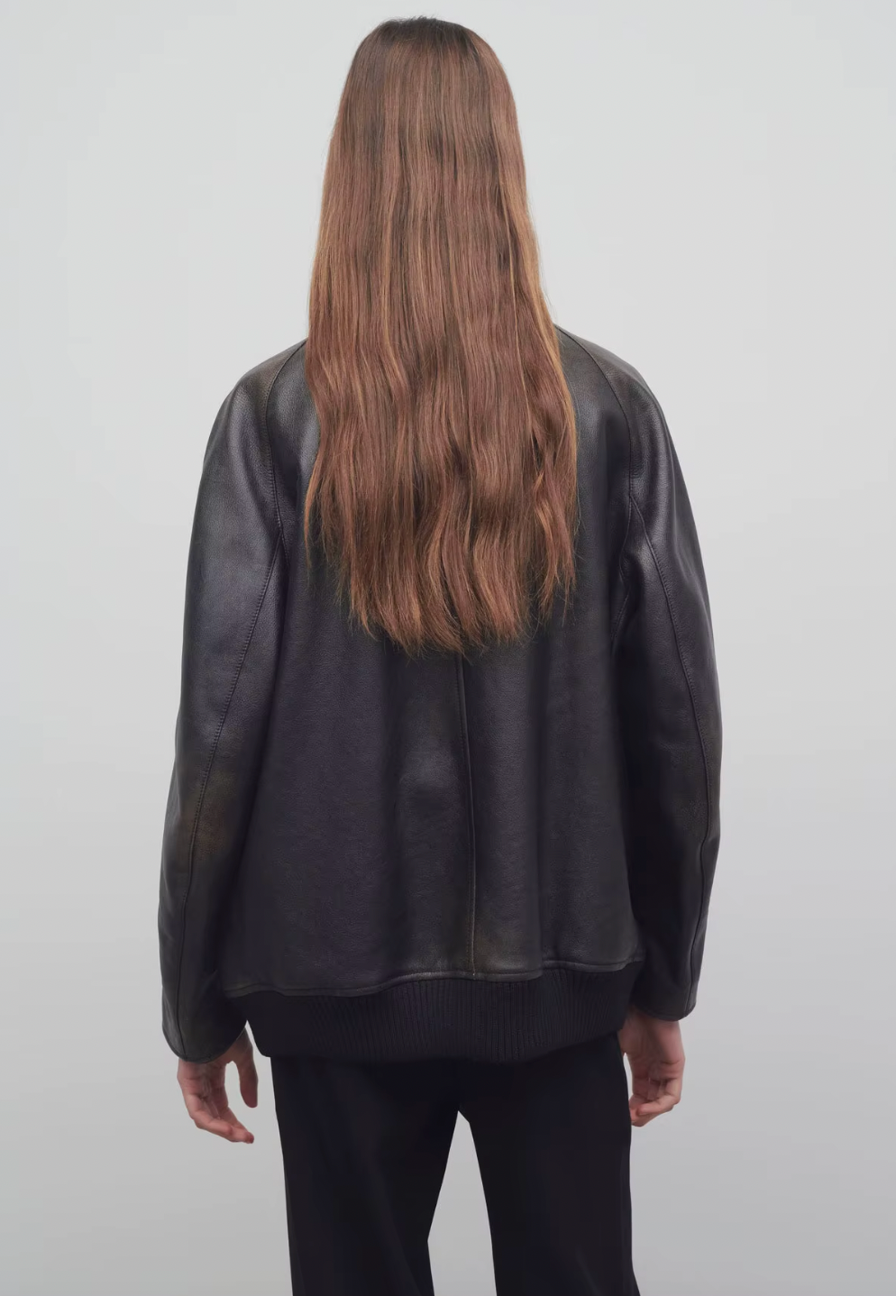 The Row brown oversized motorcycle jacket in distressed calfskin leather with stand collar, raglan sleeves, side welt pockets, and ribbed hem. Finished with silver-toned front and interior cuff zippers. This jacket comes fully lined in silk Habotai.