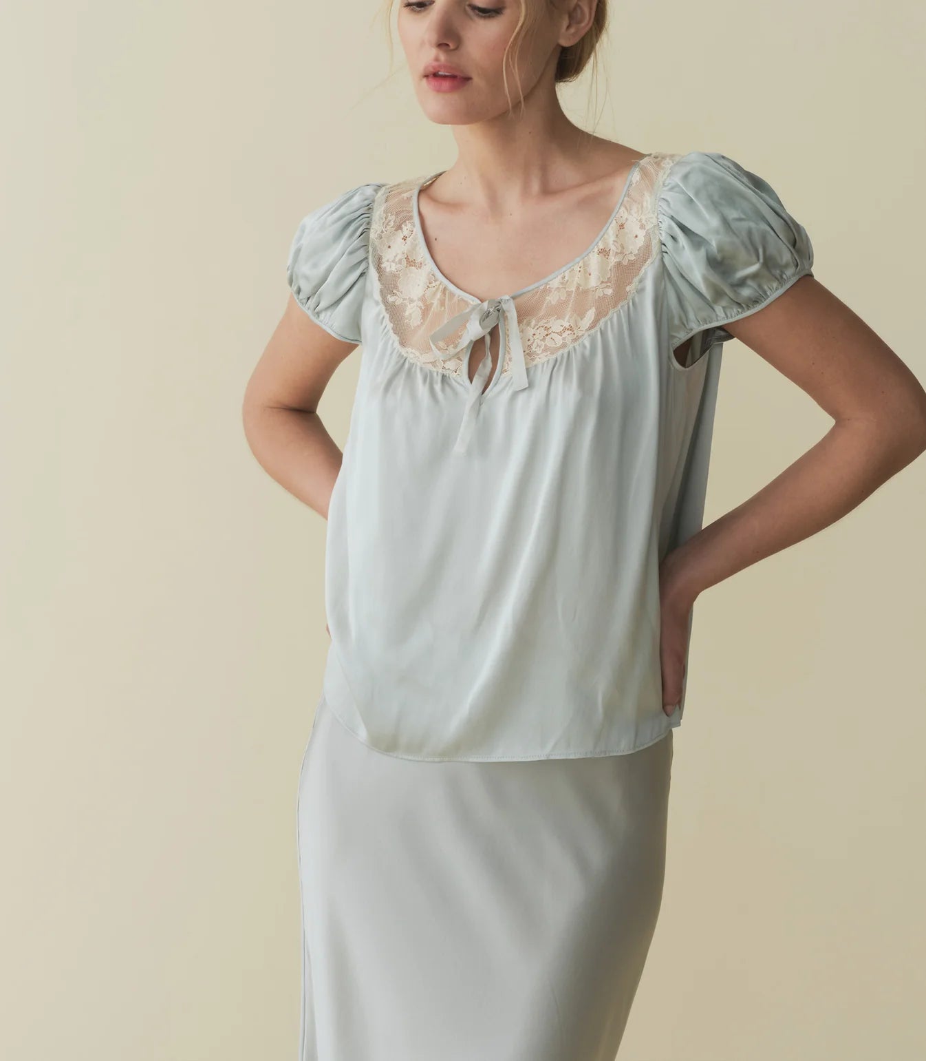 The luxurious Camri Top exudes an effortless style and understated elegance. Crafted from buttery silk satin, it features short puffed sleeves and delicate lace detailing at the yoke. Inspired by the glamour of the 1930s, it is completed with a delicate silk satin tie at the center front. Elevate your wardrobe with this timeless piece.