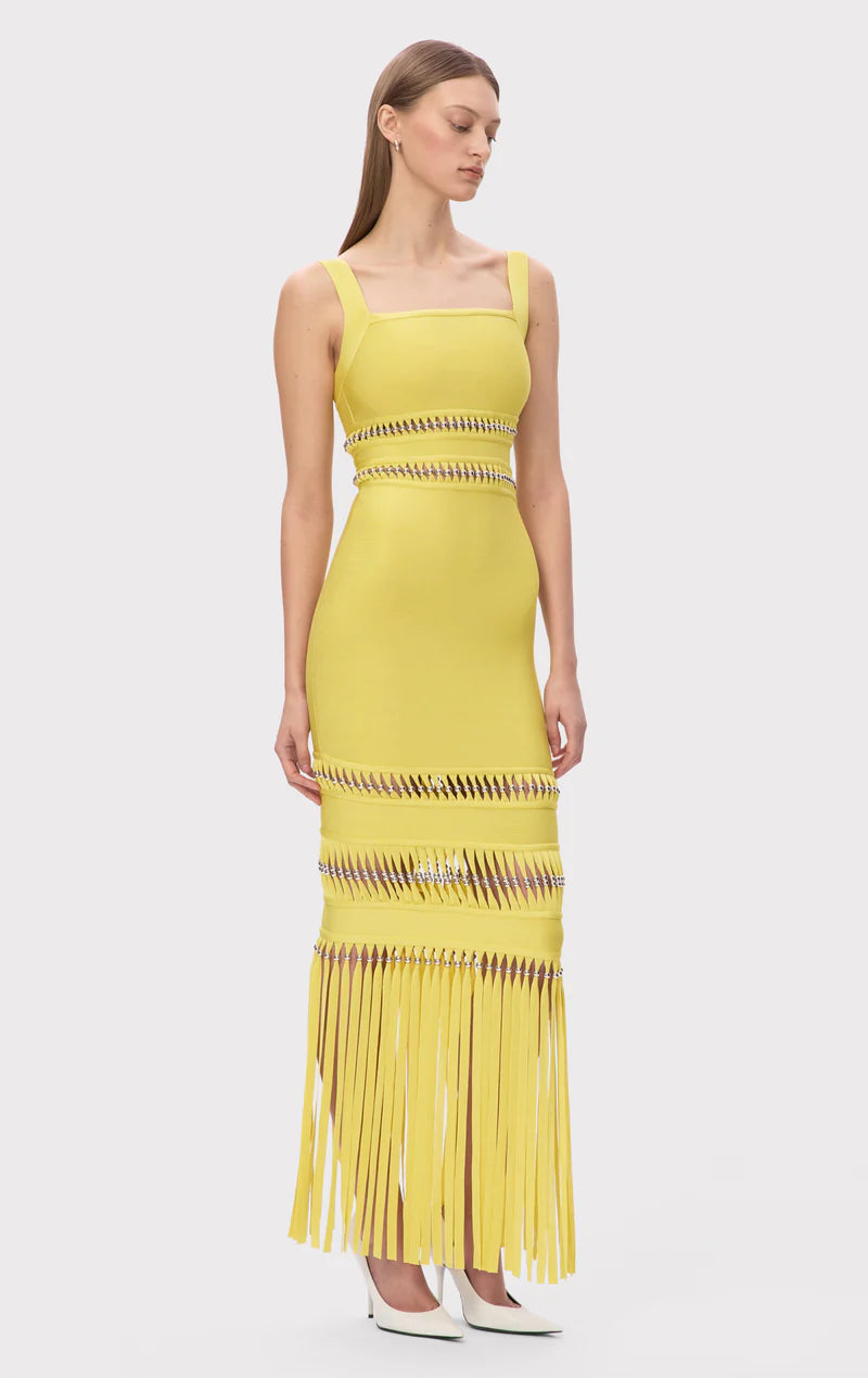 The Ines Gown by Herve Leger is a masterpiece of contemporary sophistication. Its body-contouring midi silhouette flatters every curve, while the striking square neckline commands attention. Hand-placed silver beads catch the light beautifully, creating an enchanting shimmer that draws the eye. Strategic cutouts offer tasteful glimpses of skin, adding an element of allure without compromising elegance. 