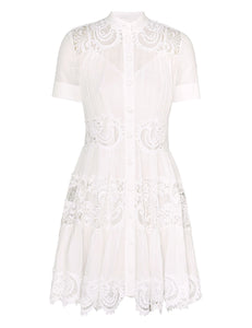 This cotton mini dress features short sleeves and a front center placket for a polished look. Its delicate scalloped hemline and intricate placement trim add refined detailing, while the included separate slip ensures comfortable coverage and smooth layering. Ideal for warm weather, this dress combines breathable fabric with elegant design elements.