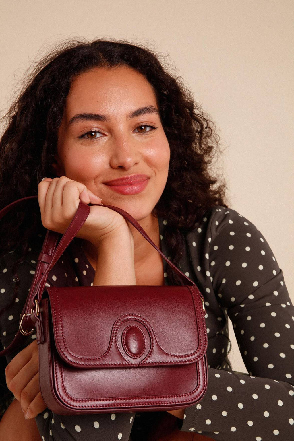 The Sac a main Bibi Nappa is the perfect accessory for any outfit. Made from 100% smooth cow leather, this small bag features a stylish "R" embossed flap with a magnetic closure. With its sleek design and bold burgundy color, it's both functional and fashionable.