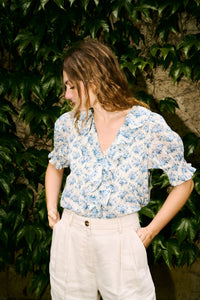 The Henri Top is a stunning blend of romantic Victorian aesthetics and modern sophistication. Made from soft, lightweight organic cotton voile, it features a plunging V-neckline adorned with cascading lace-trimmed ruffles. Delicate clustered pintucks accent the yoke and puffed sleeves, while hidden starburst buttons add a unique touch. Perfect for both casual outings and special occasions, this blouse effortlessly elevates any outfit with its vintage charm and playful elegance.