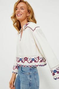 The Soren Embroidery Long Sleeve Top from Sea New York combines effortless style with sophisticated details. Crafted from soft cotton, this blouse features a collared V-neckline and long bell sleeves with subtle shoulder pleats for a refined silhouette. Elegant contrast embroidery adorns the hem and cuffs, adding a delicate, feminine touch. Versatile and modern, it pairs seamlessly with denim and flats for an easy yet polished look that channels boho-chic cool with understated elegance.