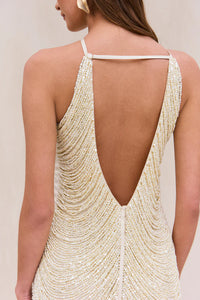 Indulge in the luxurious and exclusive Domina Dress by Cult Gaia. This exquisite halter dress boasts a layered and draped faux pearl fringe that gracefully moves with you. The plunging open back and flattering v-cut silhouette make this mini dress a must-have for any elegant occasion. Elevate your style with this captivating piece.