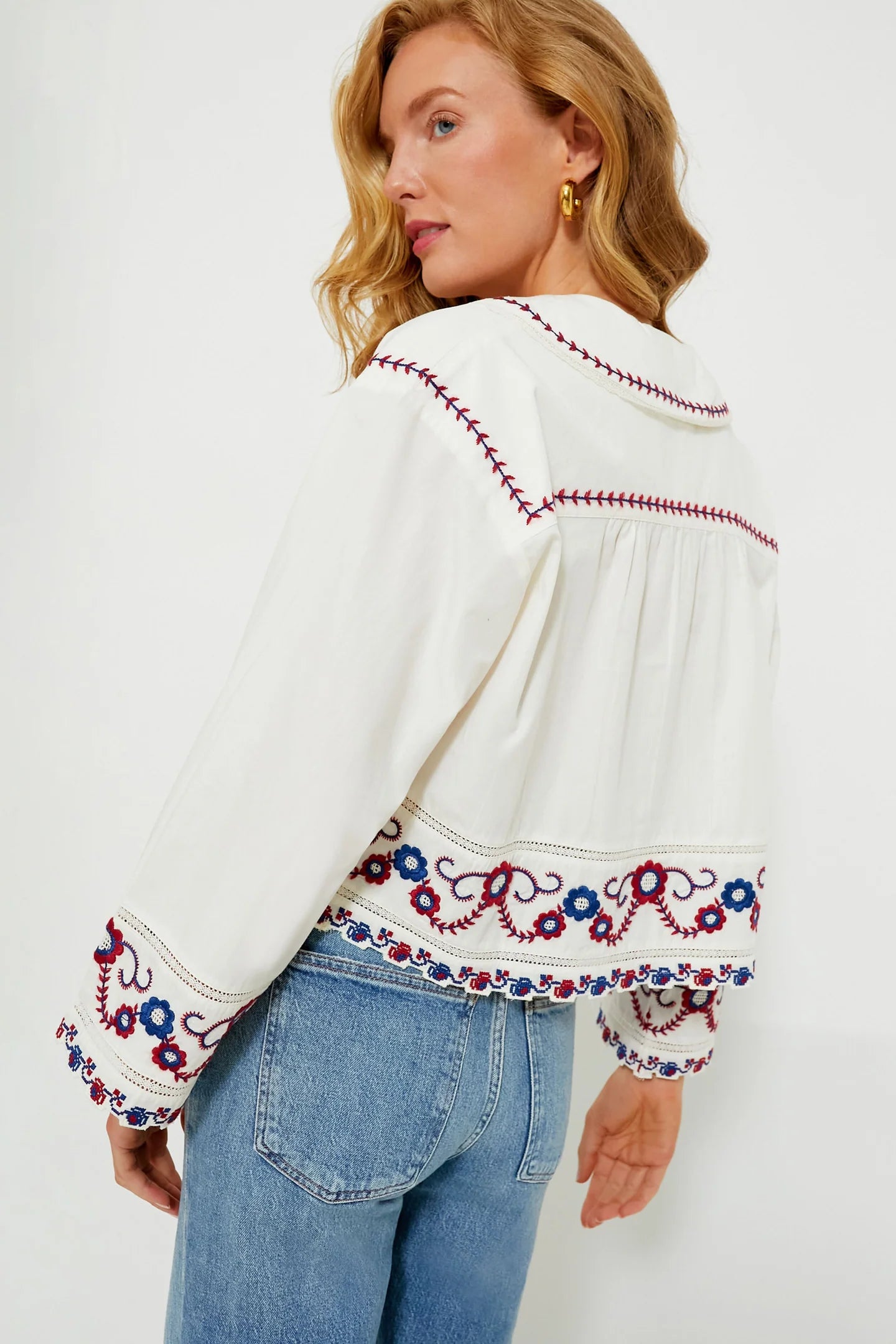 The Soren Embroidery Long Sleeve Top from Sea New York combines effortless style with sophisticated details. Crafted from soft cotton, this blouse features a collared V-neckline and long bell sleeves with subtle shoulder pleats for a refined silhouette. Elegant contrast embroidery adorns the hem and cuffs, adding a delicate, feminine touch. Versatile and modern, it pairs seamlessly with denim and flats for an easy yet polished look that channels boho-chic cool with understated elegance.