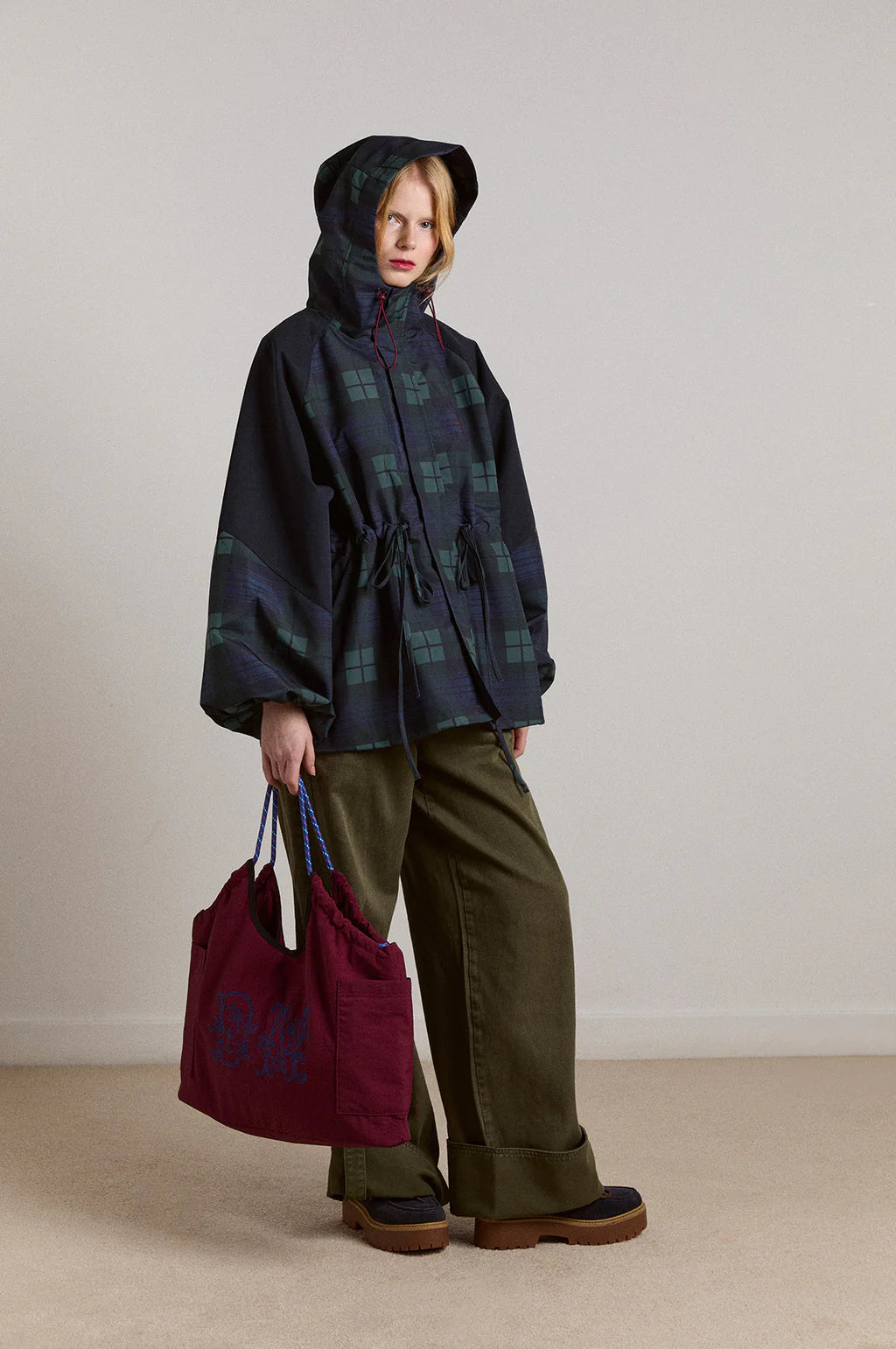 Embrace rainy days with the Liu Coat from Damson Madder, featuring a classic Black Watch tartan design crafted from shower-resistant fabric. Its balloon-style cuffs, adjustable hood, and cinchable waist offer both comfort and a flattering silhouette, while signature 'DM' embroidery adds a touch of distinction. Equipped with practical pockets and thoughtful details, this coat effortlessly combines style and functionality, making it the perfect shield against wet weather.