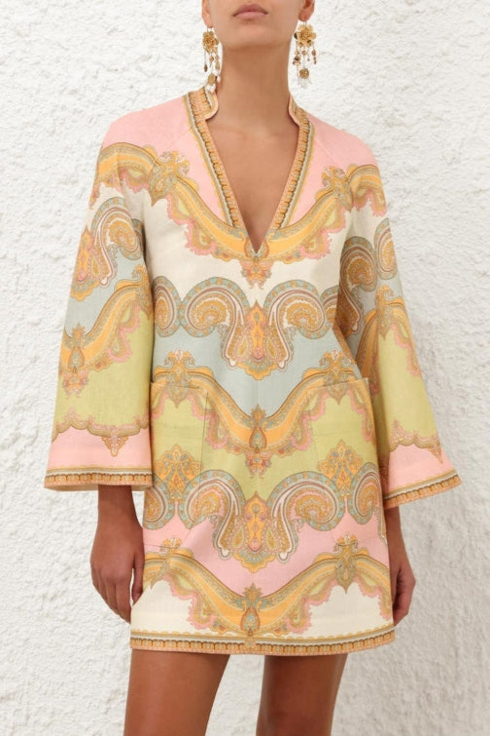 Elevate your resort wardrobe with the Maxine Tunic Mini Dress in Gold Paisley by Zimmermann. Crafted from breathable linen, this dress features a flattering deep V-neckline, stylish wide sleeves, and convenient patch pockets for effortless chic. The center back zip ensures a perfect fit, making it your go-to piece for both relaxed days and elegant evenings.