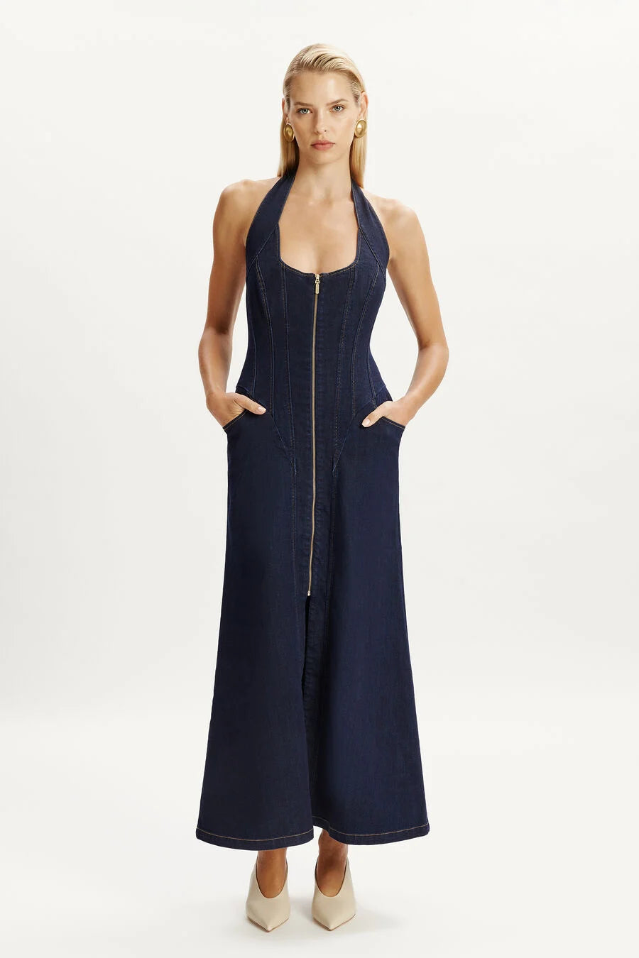 Discover the Martel Denim Midi Dress by Bardot—where casual charm meets refined elegance. This contemporary piece features a flattering halter neck and structured corset bodice that sculpts and supports, while the flared midi skirt with an open front split adds movement and sophistication. Practical side pockets keep you comfortable, and the versatile design transitions seamlessly from day to night. 