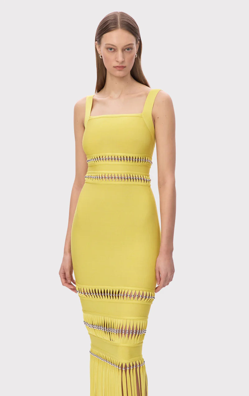 The Ines Gown by Herve Leger is a masterpiece of contemporary sophistication. Its body-contouring midi silhouette flatters every curve, while the striking square neckline commands attention. Hand-placed silver beads catch the light beautifully, creating an enchanting shimmer that draws the eye. Strategic cutouts offer tasteful glimpses of skin, adding an element of allure without compromising elegance. 